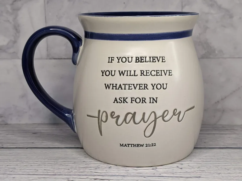 A blue and white religious coffee mug with a Scripture about prayer from Matthew 21:22.