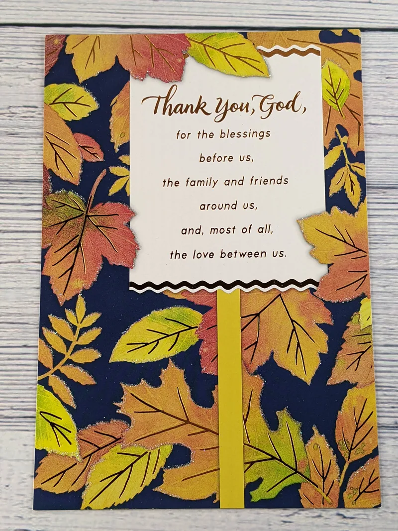 A religious Thanksgiving greeting card with a blue cover that has images of leaves and glittery accents.