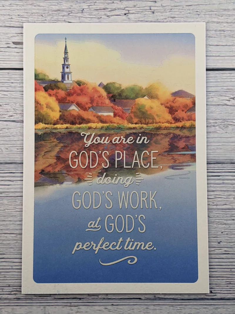 A greeting card with an image of a church steeple and autumn trees reflecting in the water.