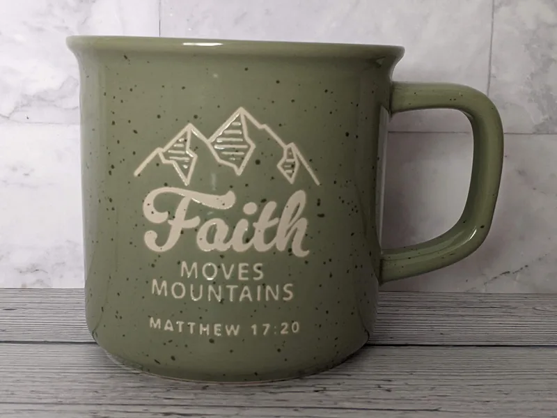 A green Christian mug with a verse, "Faith Moves Mountains."