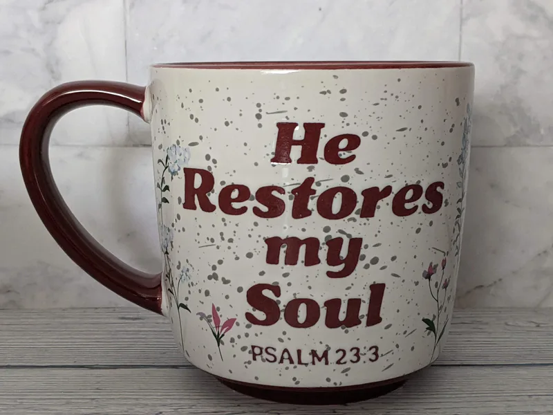 A Christian mug with a Bible verse, "He restores my soul."