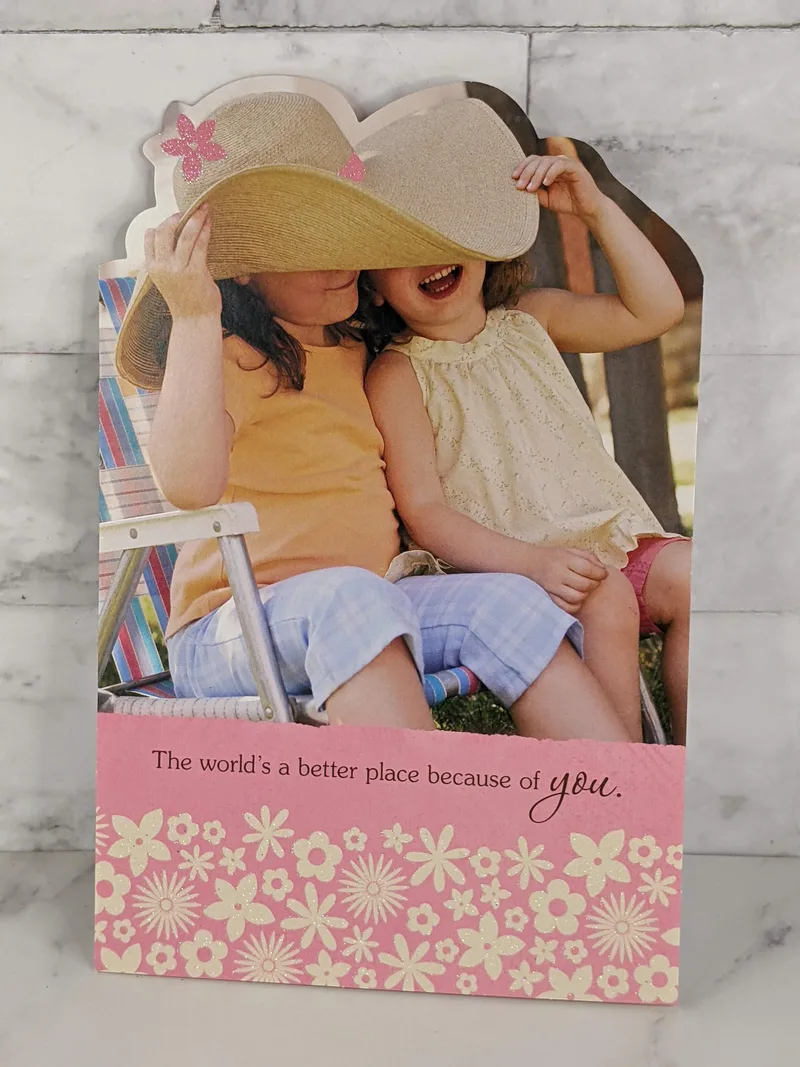 A religious friendship greeting card that features an image of two girls together wearing a huge hat.