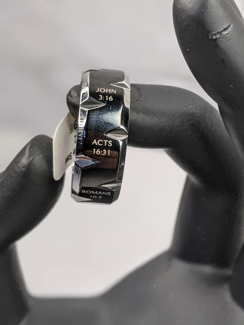 A silver ring for a man with a notched design and a black enamel coating with inscribed references of Bible verses.