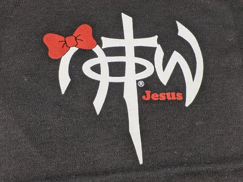 A one-piece baby outfit shirt that is black with a NOTW logo and a red bow design.