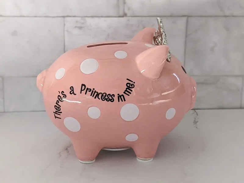 This cute pink coin bank is shaped like a pig wearing a crown, and features the words, "There's a princess in me."