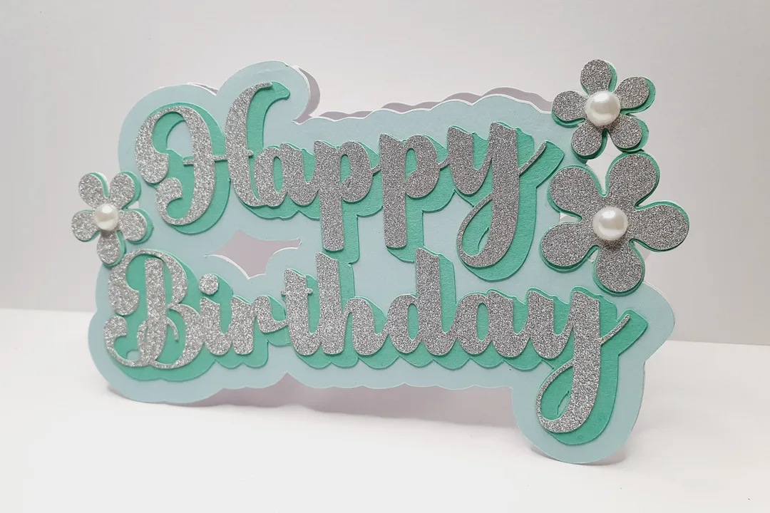 Image shows a layered papercut birthday card designed by The Makewell Paper Co.with the words Happy Birthday and floral embellishments.