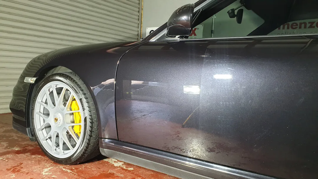 Porsche 911 during machine polishing showing the difference on one section of door