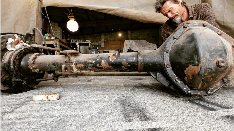 Man with the front axle off a 1970s Bedford truck