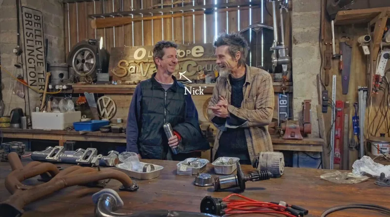 2 men stand at a workbench in a workshop