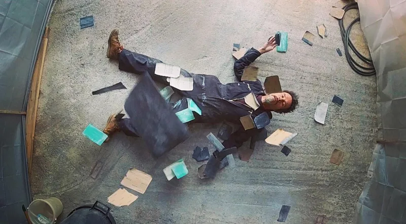 Man in overalls lying on floor surrounded by used sanding blocks