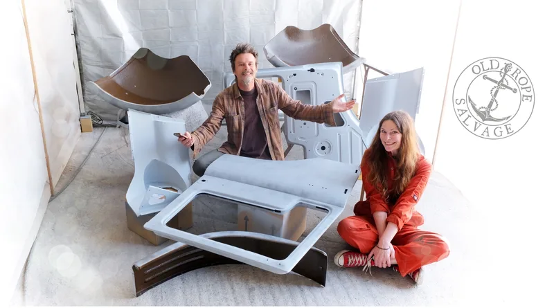 Man and woman sitting in a paint spray Booth with Bedford truck panels in grey primer