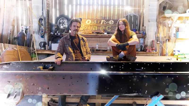 Man and woman with a half painted truck chassis frame