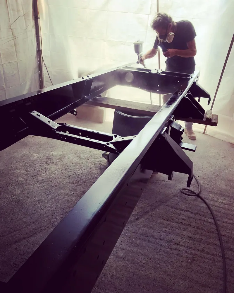 Man spray painting a truck chassis frame
