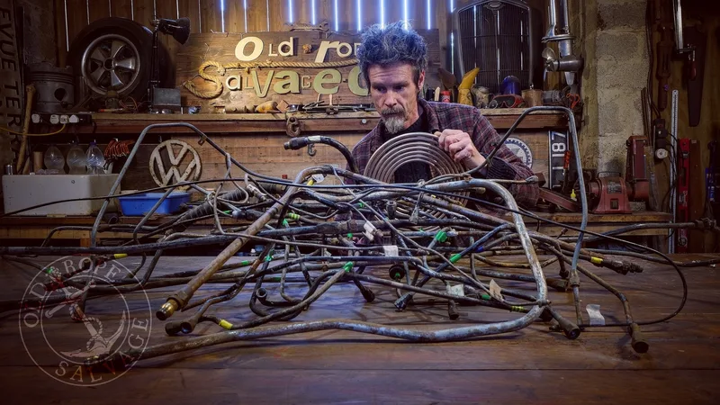 Man standing at a workbench with tangled metal airlines and brake lines in front of him