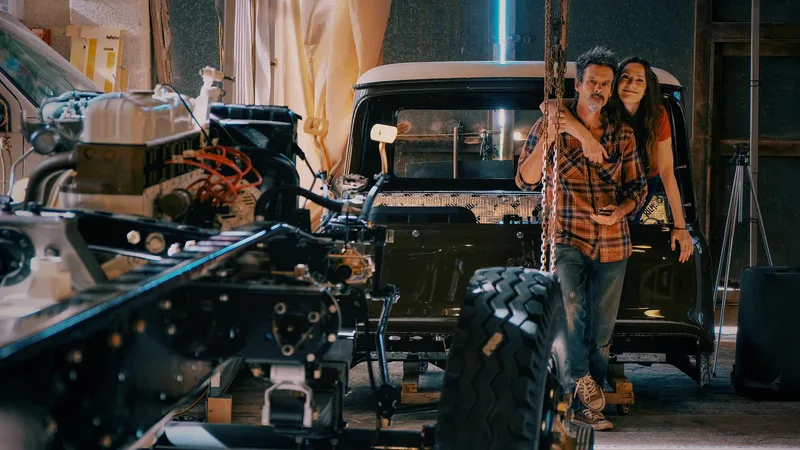 Man and woman stand with a 1970s Bedford truck in the process of being restored