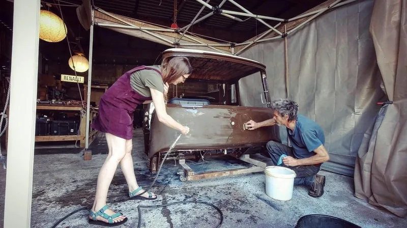 Man and woman in a workshop sanding and polishing the paintwork on a Bedford truck cab