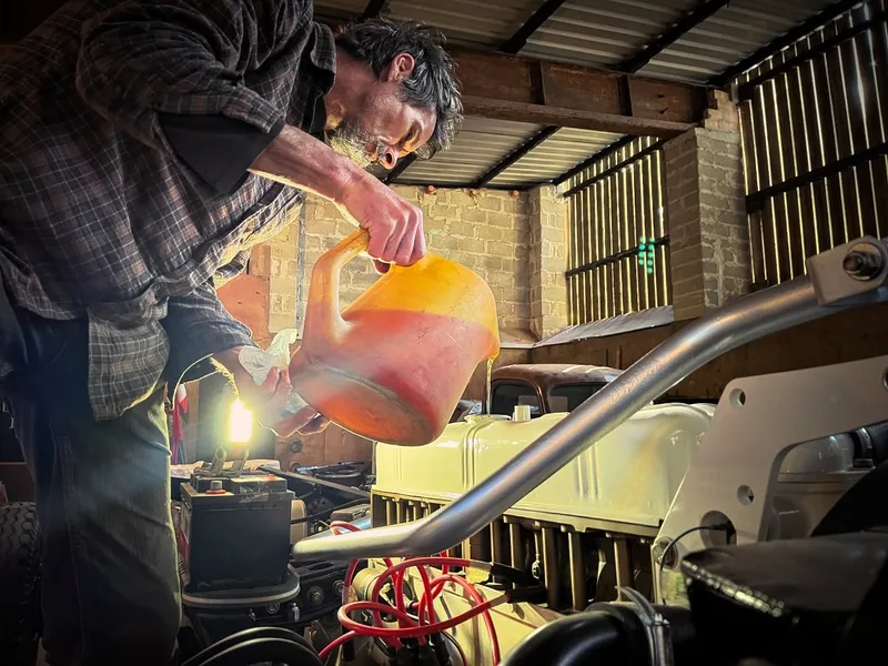 Man filling a Bedford truck petrol engine with oil