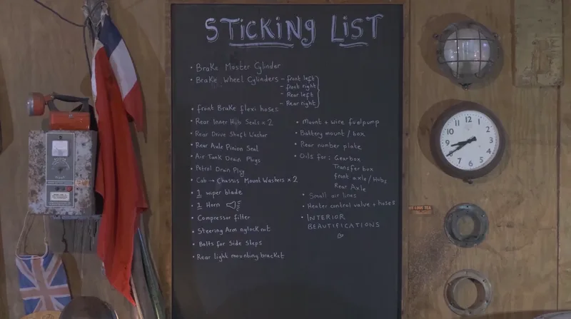 A chalkboard with a list of jobs and car parts titled ‘sticking list’